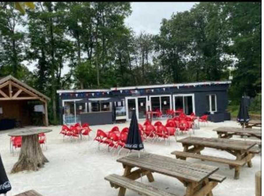 un groupe de tables et de chaises de pique-nique devant un bâtiment dans l'établissement Mobil home, à Saint-Chéron