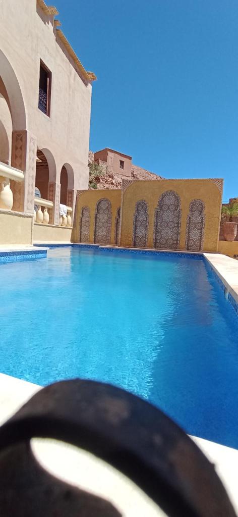 une grande piscine bleue à côté d'un immeuble dans l'établissement Riad Villa Dades, à Boumalne