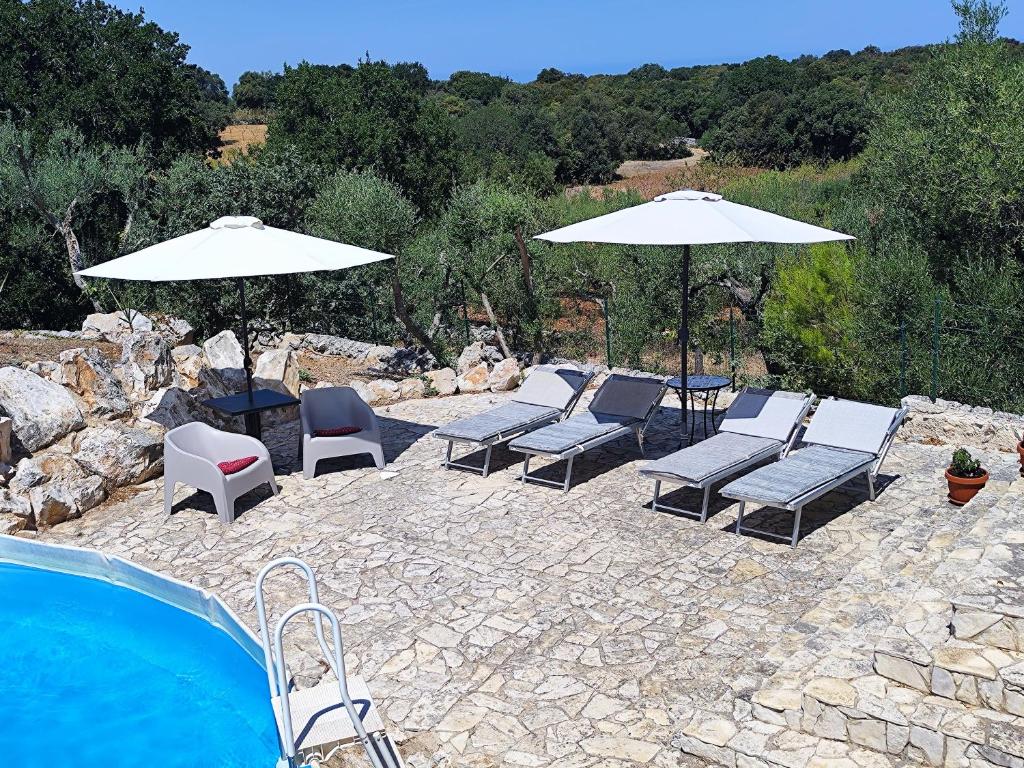 - un groupe de chaises longues et de parasols à côté de la piscine dans l'établissement Trullocarluccio, à Monopoli