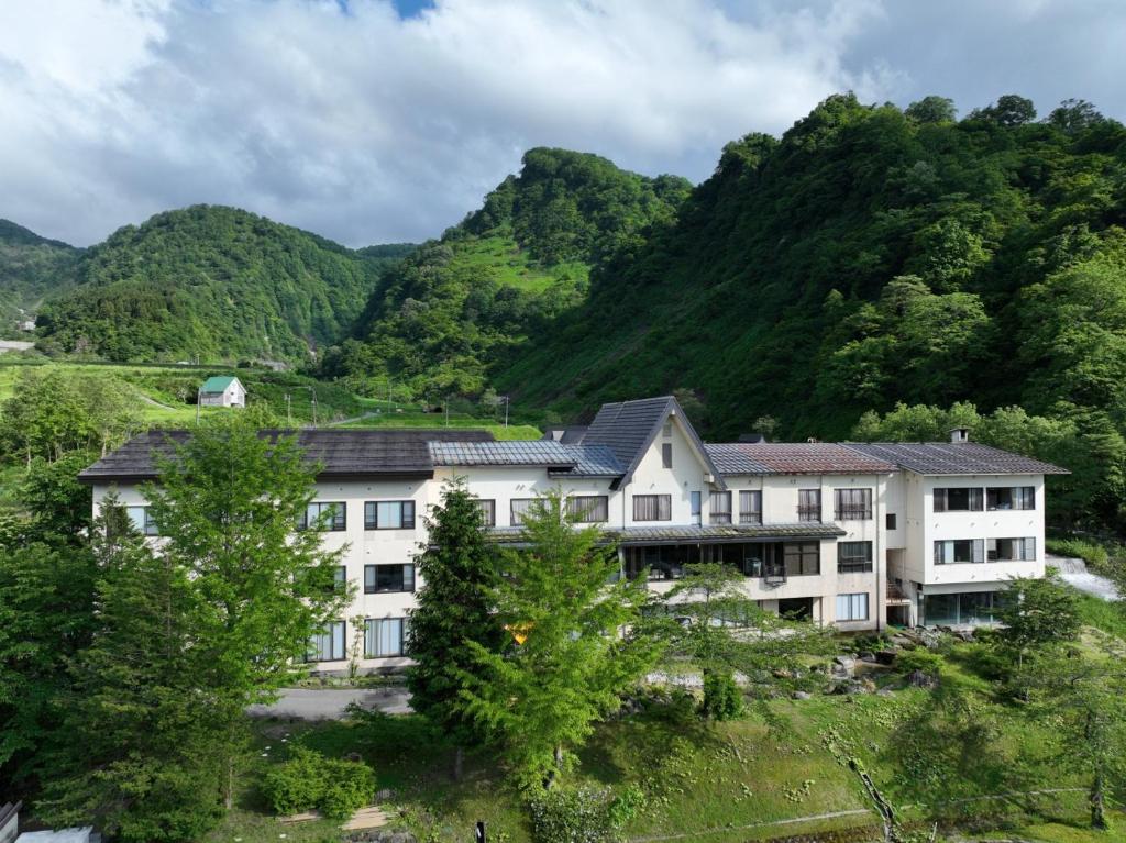 un immeuble situé en face d'une montagne dans l'établissement Sasakura onsen Ryuunso, à Itoigawa