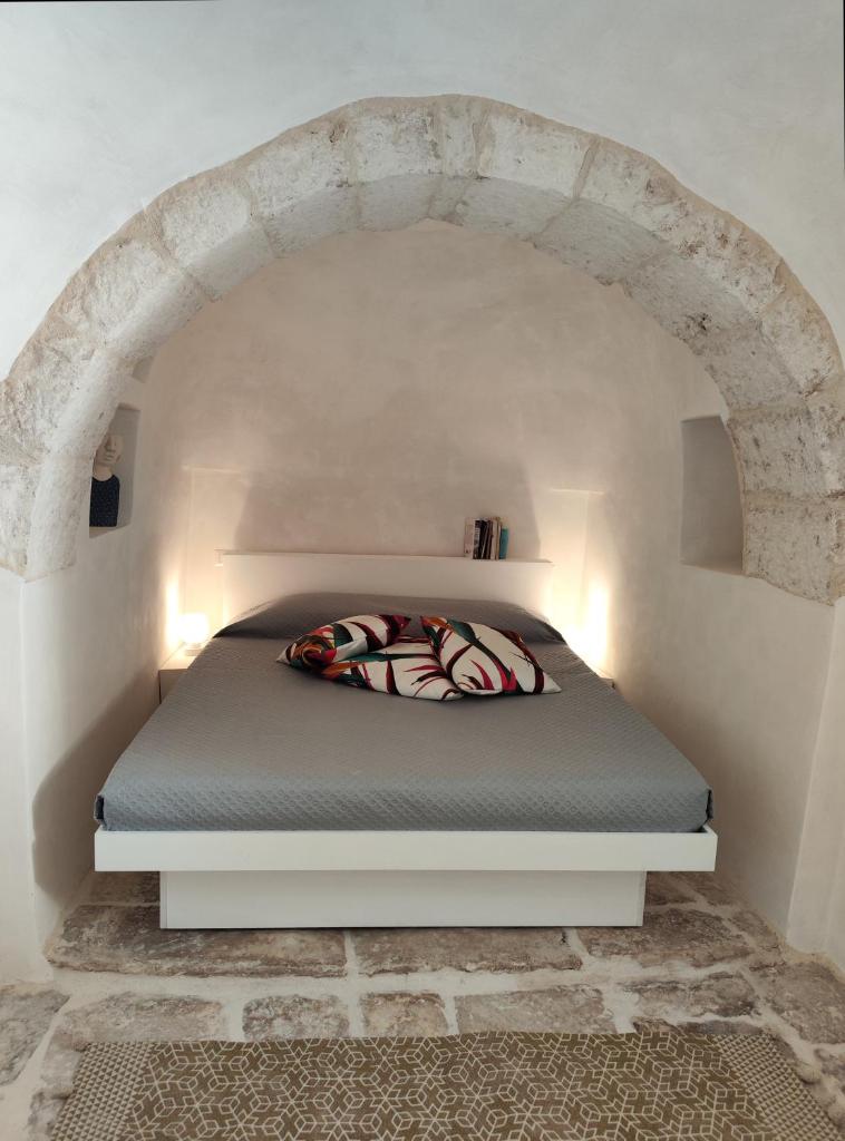un lit dans une chambre blanche avec une arche dans l'établissement Trulli Pace 1879 Martina Franca, à Martina Franca