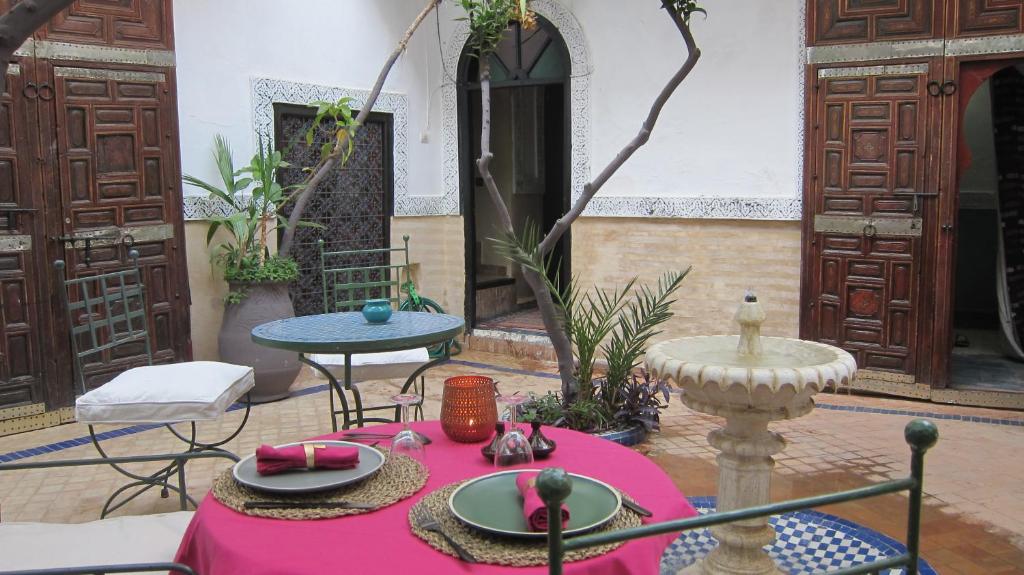 une table avec un tissu de table rose dans une cour dans l'établissement Riad Maizie, à Marrakech