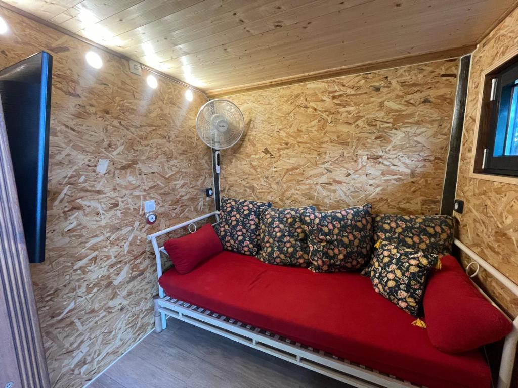 - un canapé rouge dans une chambre dotée d'un mur en pierre dans l'établissement Les lucioles cabane chalet avec Jacuzzi privatif, à Privas