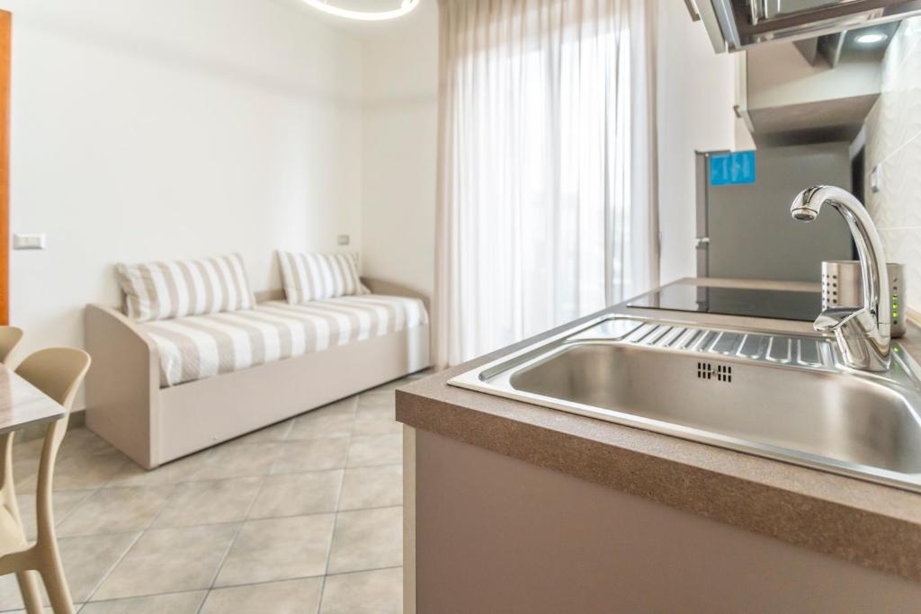 une cuisine avec un évier et un salon avec un canapé dans l'établissement Residence Rimini Relax, à Rimini