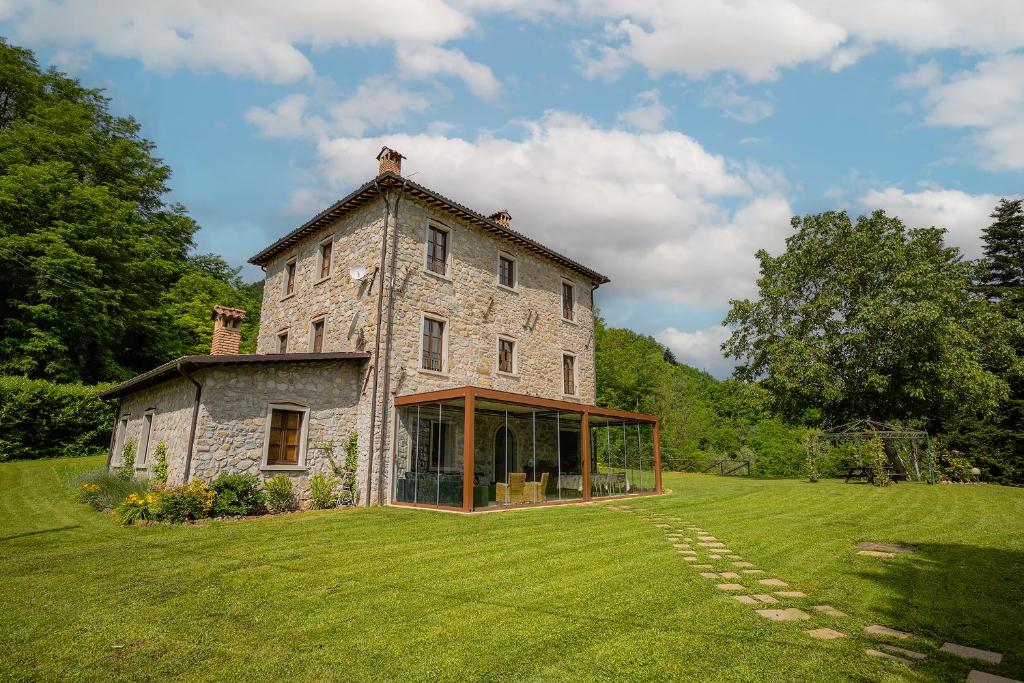 une ancienne maison en pierre sur une pelouse dans l'établissement Villa Casa di Pietra en el norte de Lucca, Toscana, à Camporgiano