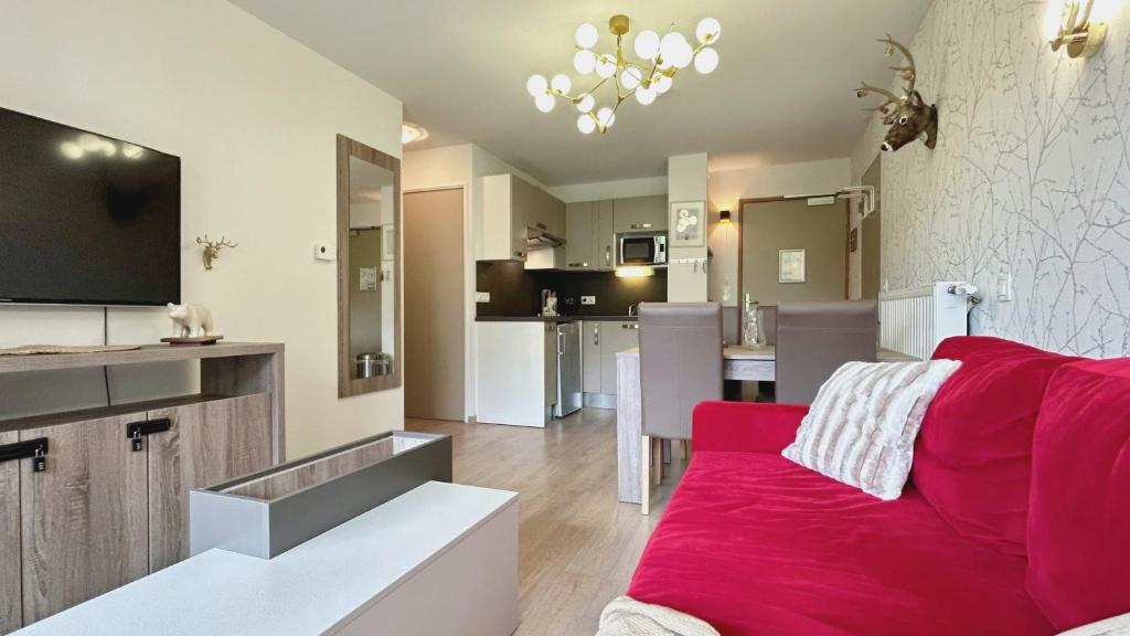 un salon avec un canapé rouge et une cuisine dans l'établissement Crests Lodge - Plagne -Villages 2100m - Classé 4 étoiles, à La Plagne Tarentaise