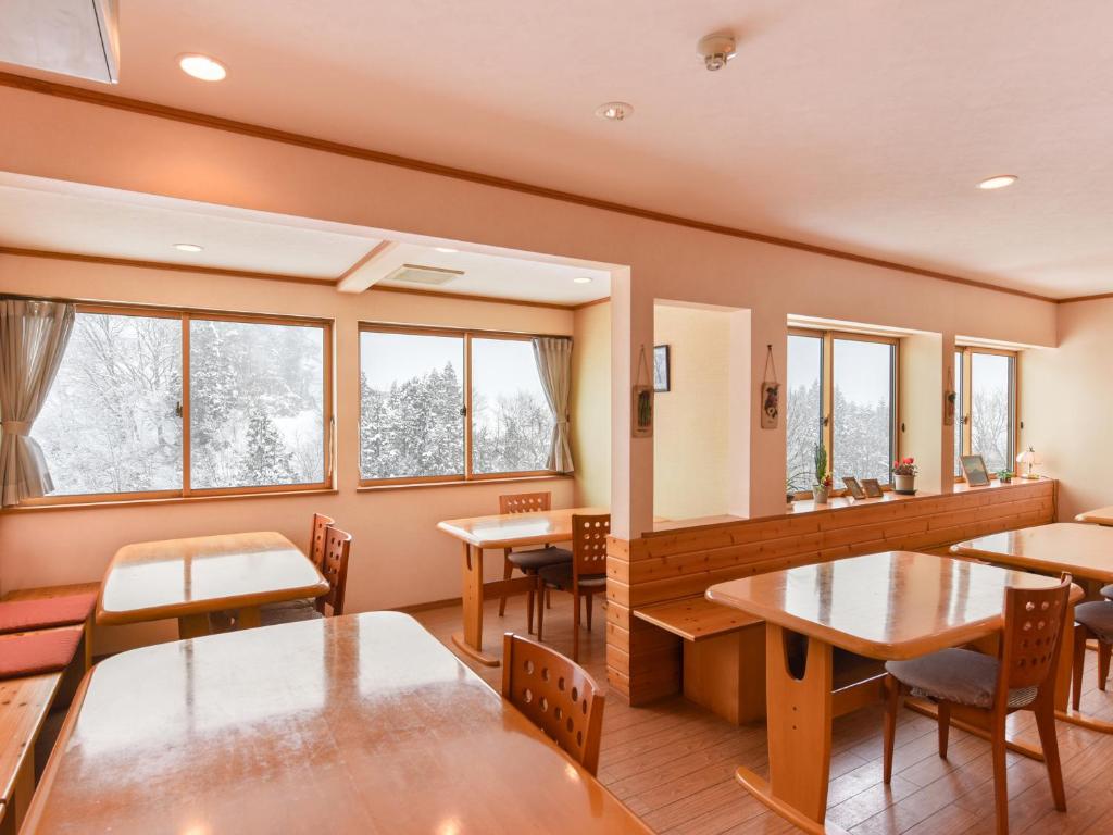 une salle à manger avec tables, chaises et fenêtres dans l'établissement Akakura onsen eho ryokan, à Myōkō
