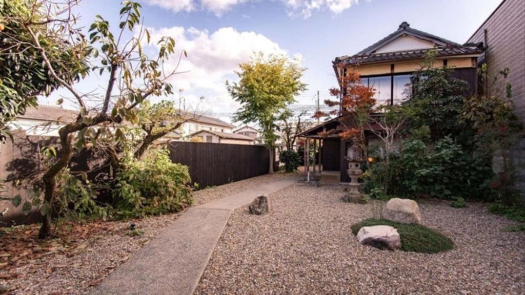 un jardin avec des rochers, une clôture et une maison dans l'établissement NIPPONIA Sasayama Castle Town Hotel, à Sasayama