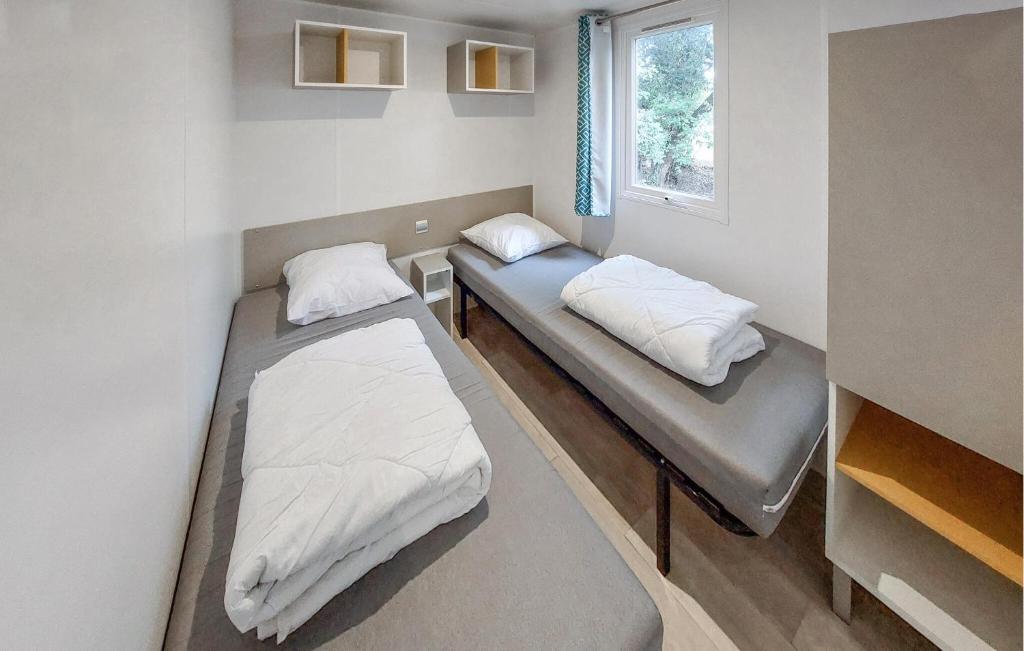 deux lits dans une petite pièce avec une fenêtre dans l'établissement Mobile Home Moderne, à Saint-Hilaire-de-Talmont