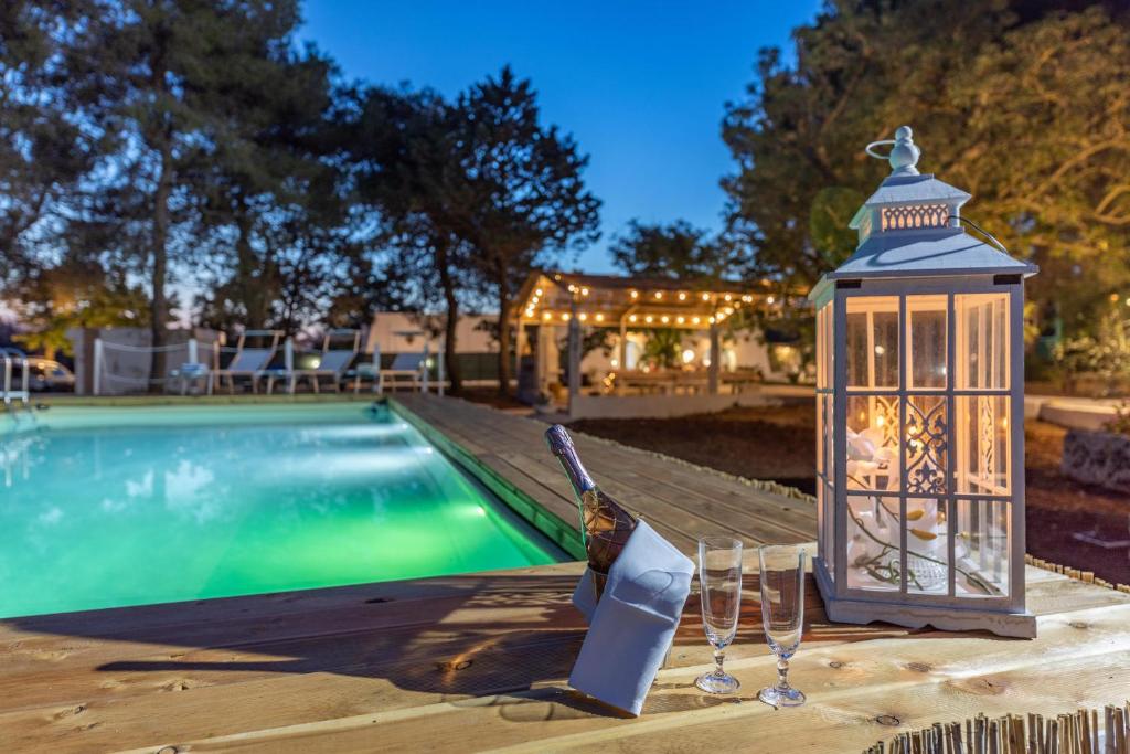 une lanterne et des verres à vin à côté d'une piscine dans l'établissement Villa Le Terracate, à Lido Marini