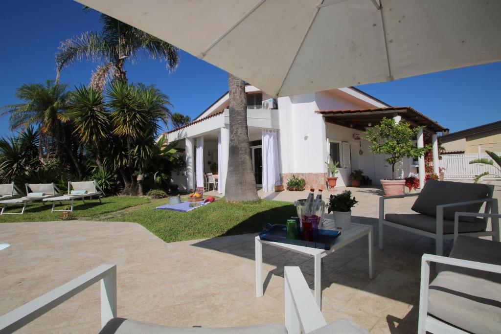 un patio avec tables, chaises et un parasol dans l'établissement Edri beach house - Villa con piscina, à Pontecagnano