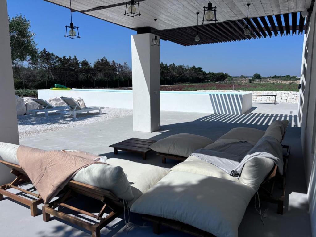 un groupe de lits sur un patio à côté d'une piscine dans l'établissement Aeneas Villa Pool & Jacuzzi al mare Torre Guaceto, à Specchiolla
