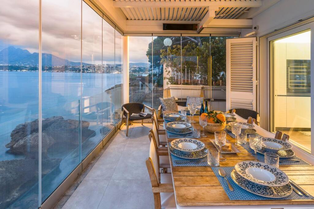 - une table à manger sur un balcon avec vue sur l'eau dans l'établissement Design house with pool & direct access to the sea, à Santa Flavia