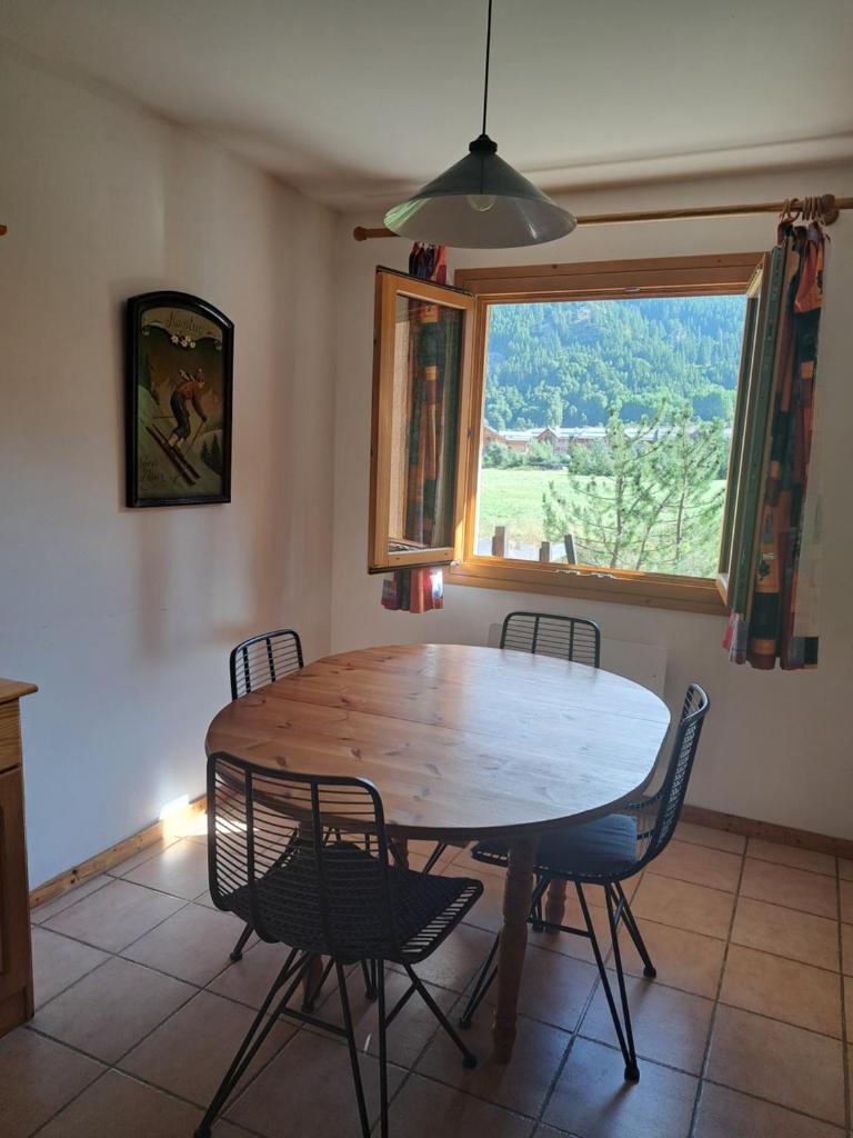 une table de salle à manger avec des chaises et une grande fenêtre dans l'établissement Marmotte Le Monêtier Apartment, au Monêtier-les-Bains