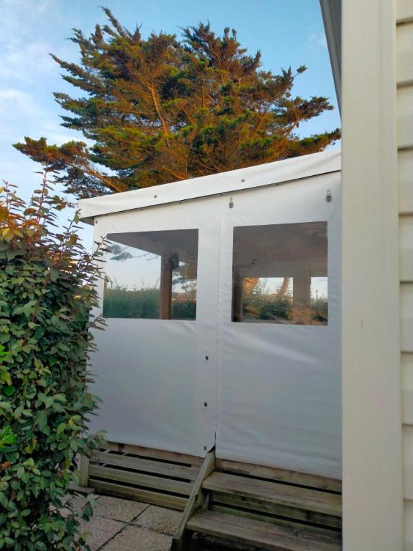 un garage blanc avec deux fenêtres et un arbre dans l'établissement mobilhome, à Bretignolles-sur-Mer