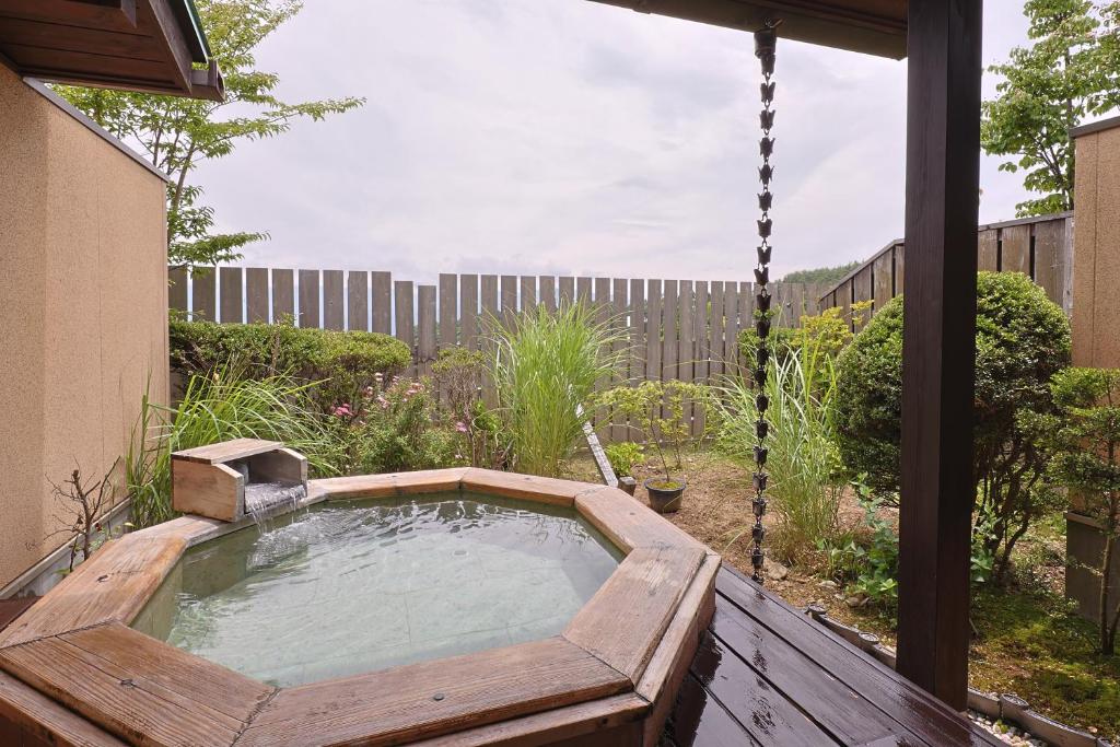 un bain à remous dans un jardin avec une balançoire dans l'établissement 和みの湯宿なかやま, à Komagane