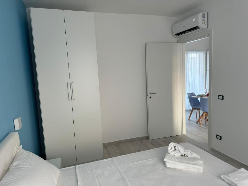 une chambre avec un lit blanc et un miroir dans l'établissement SUNSHINE LUXURY APARTMENTS - Private Pool and Beach - Policoro Lido, à Policoro