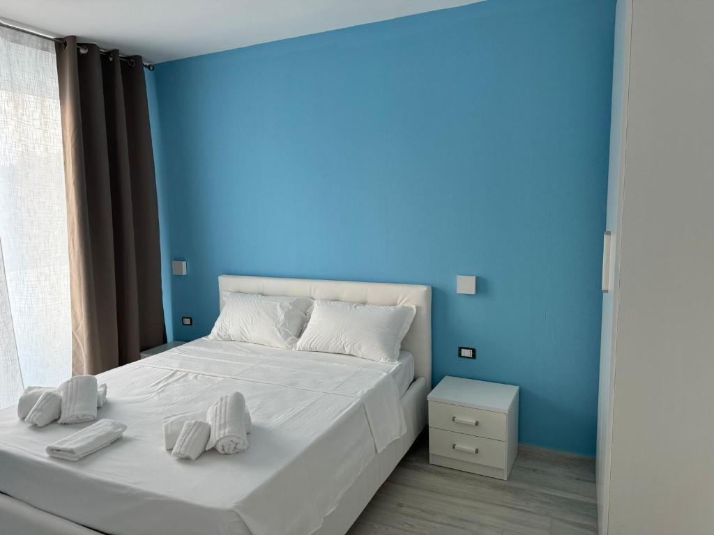 une chambre avec un lit blanc avec un mur bleu dans l'établissement SUNSHINE LUXURY APARTMENTS - Private Pool and Beach - Policoro Lido, à Policoro
