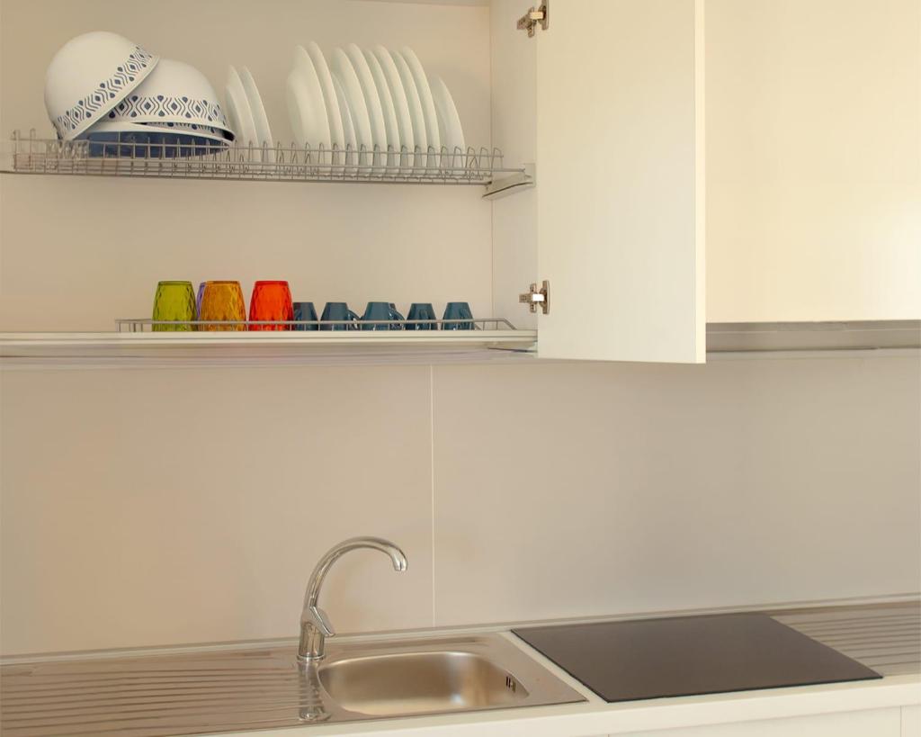 - un comptoir de cuisine avec évier et bols sur les étagères dans l'établissement SUNSHINE LUXURY APARTMENTS - Private Pool and Beach - Policoro Lido, à Policoro