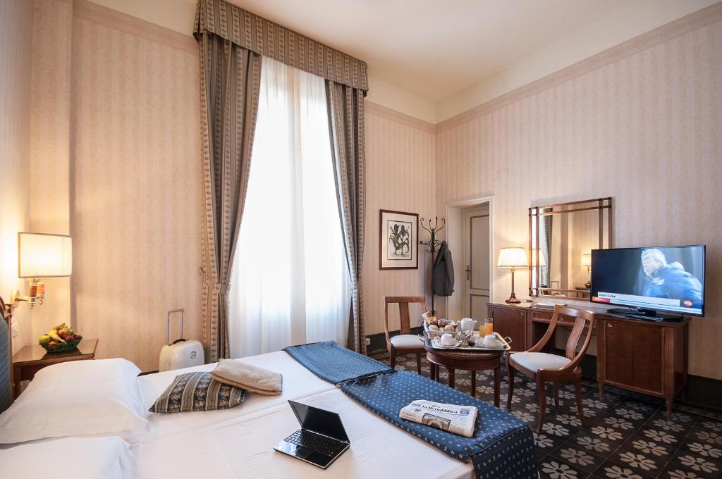 une chambre d'hôtel avec un lit et un bureau dans l'établissement Grand Hotel Royal, à Viareggio