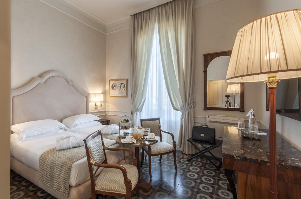 Cette chambre comprend un lit, une table et un miroir. dans l'établissement Grand Hotel Royal, à Viareggio