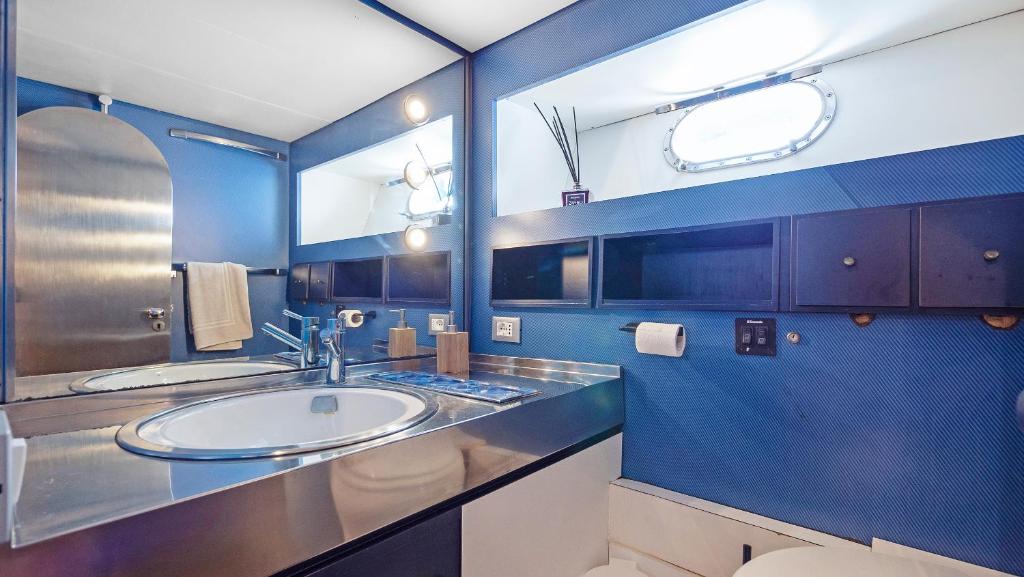 La salle de bains est pourvue d'un lavabo et d'un mur bleu. dans l'établissement Zaffiro Yacht - Festival de la plaisance Cannes 2024, à Cannes