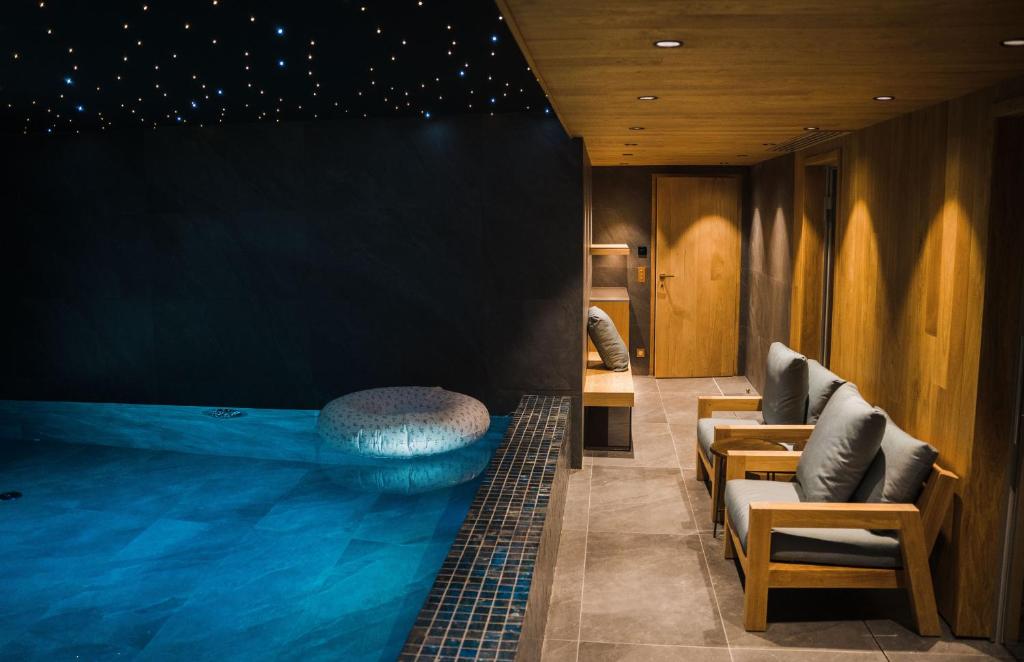 - une grande piscine dans une chambre d'hôtel avec des chaises dans l'établissement Silverstone by Alpine Resorts, à Val dʼIsère