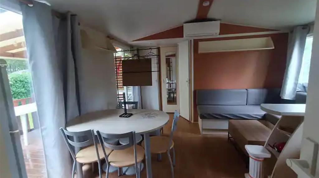 une pièce avec une table, des chaises et un canapé dans l'établissement Mobil home 2ch 5pers Tout Confort 25min PuyduFOU 710EM, à La Boissière-de-Montaigu