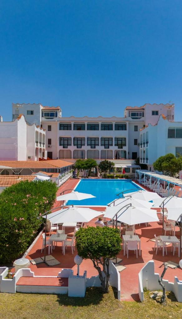 une piscine avec des tables et des parasols en face d'un bâtiment dans l'établissement International Resort, à Mondragone