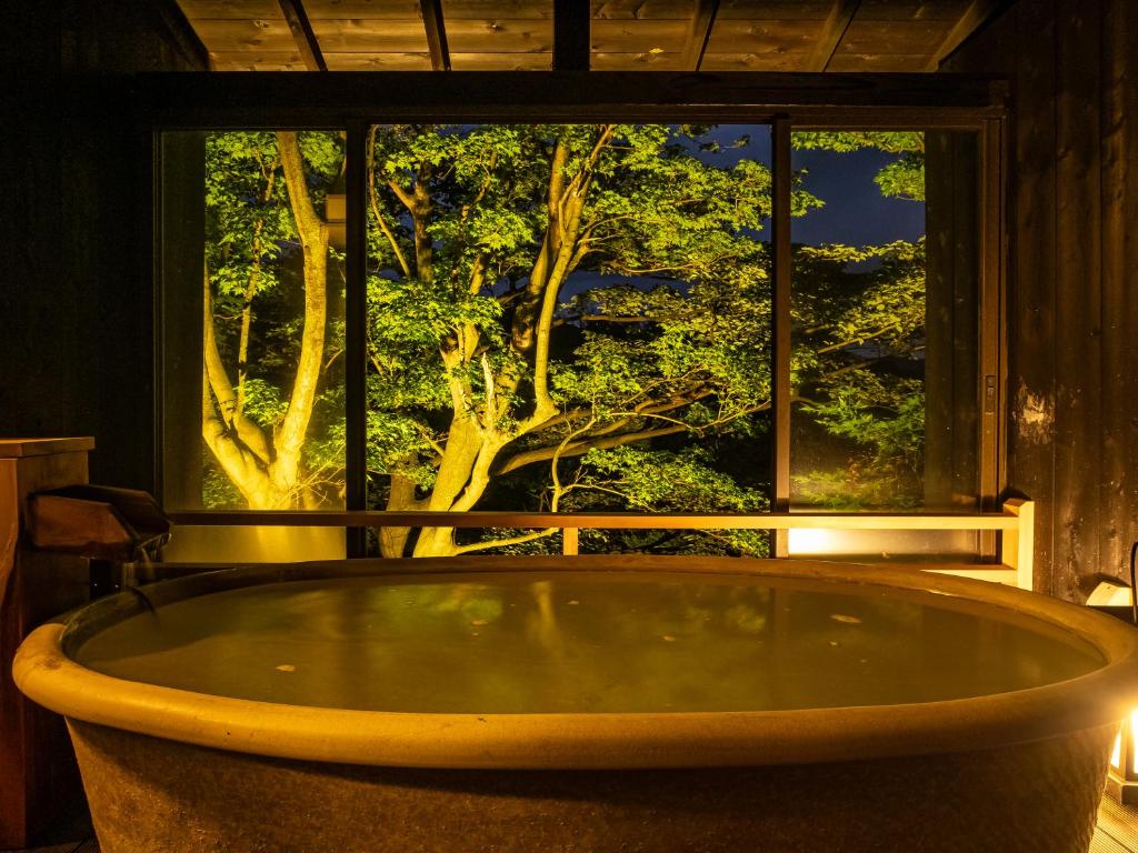 une grande baignoire en face d'une fenêtre dans l'établissement Nagominoyado Hanagokoro - Reopening in Mar 2024, à Hakone