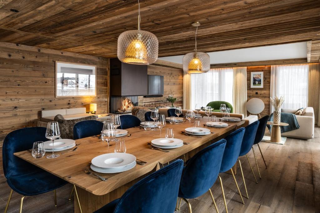 une salle à manger avec une grande table en bois et des chaises bleues dans l'établissement Silverstone by Alpine Resorts, à Val dʼIsère