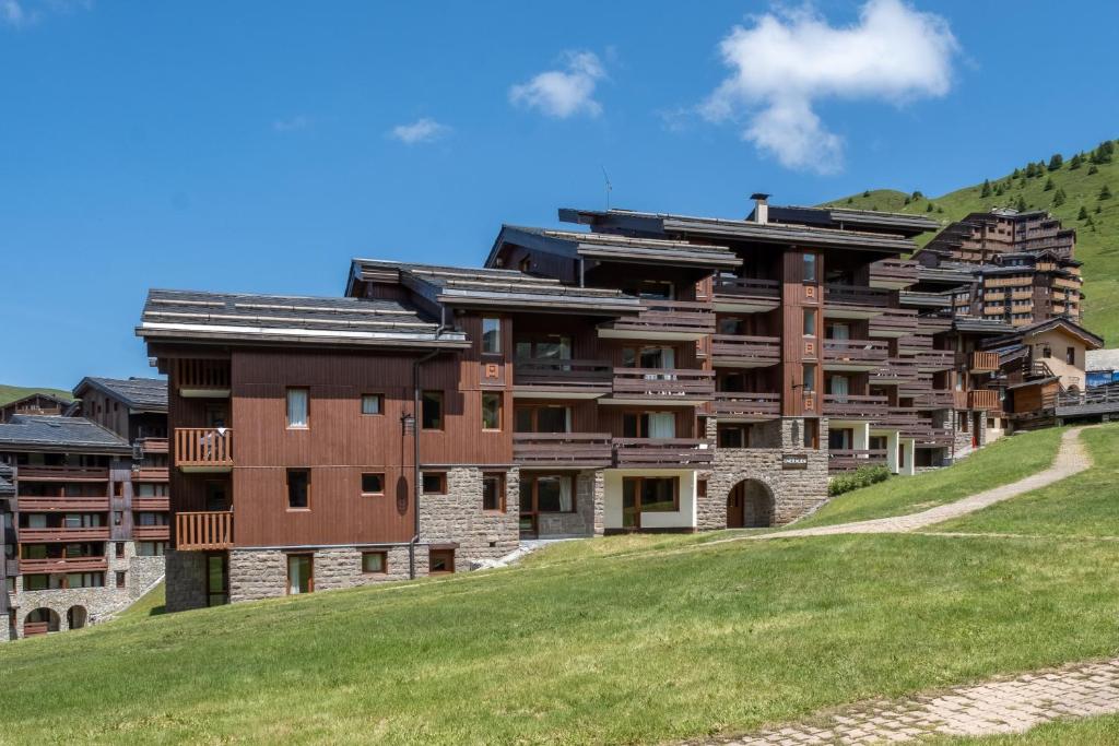 un grand bâtiment sur une colline avec un champ verdoyant dans l'établissement Résidence Pierre & Vacances Emeraude, à Belle Plagne
