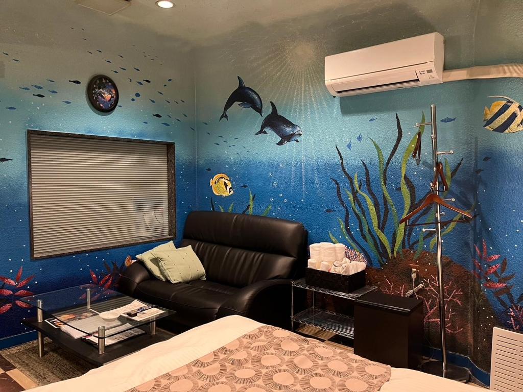 un salon avec un canapé et un mur d'aquarium dans l'établissement オーラリゾート四條畷, à Shijonawate 42 autres photos