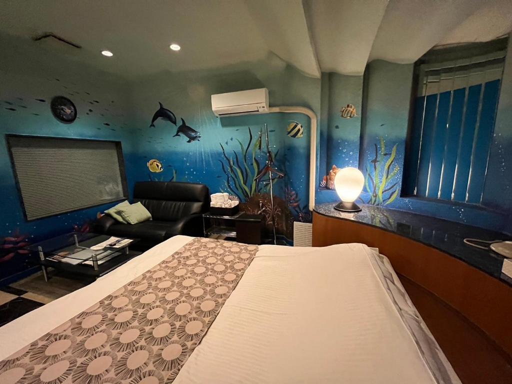 - une chambre avec un lit dans une pièce avec un aquarium dans l'établissement オーラリゾート四條畷, à Shijonawate