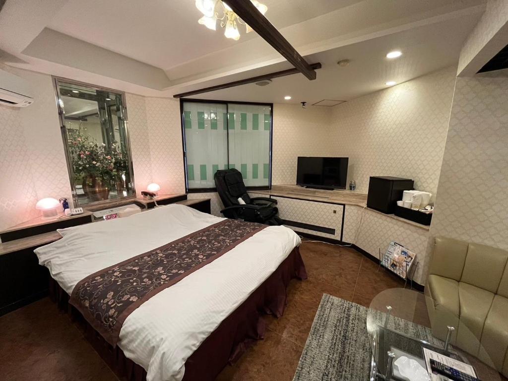 une chambre d'hôtel avec un lit et une télévision dans l'établissement オーラリゾート四條畷, à Shijonawate