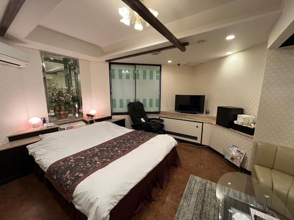 une chambre d'hôtel avec un lit et une télévision dans l'établissement オーラリゾート四條畷, à Shijonawate