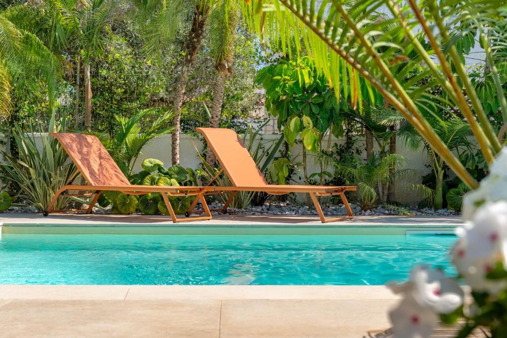 deux chaises assises à côté d'une piscine dans l'établissement Villa Bali with Pool by Wonderful Italy, à Syracuse