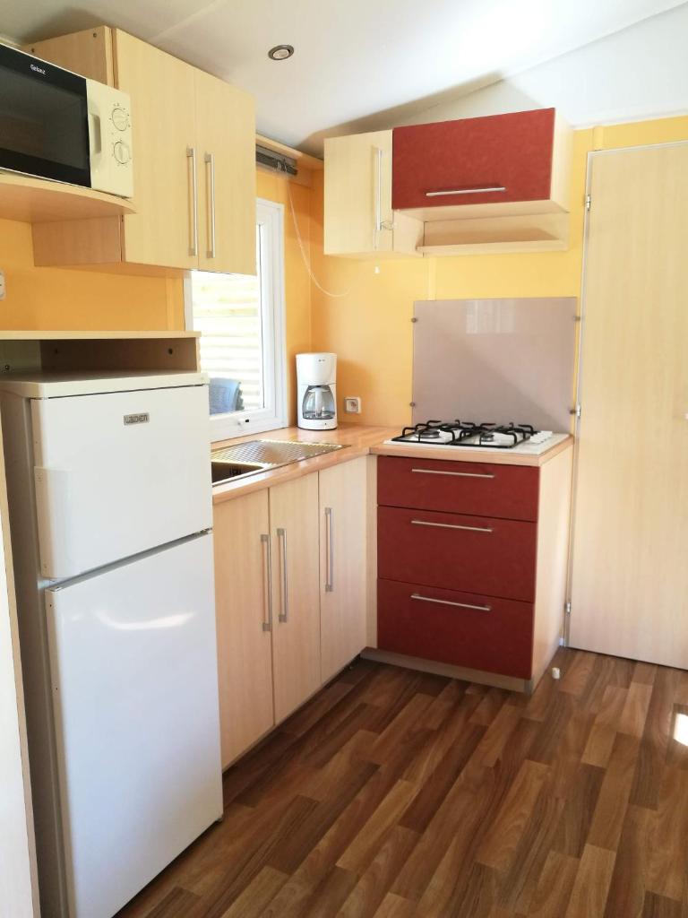 Il comprend une petite cuisine avec des appareils électroménagers blancs et du parquet. dans l'établissement Mobilhome 3 Ch climatisé à 45 mn de Paris, à Saint-Chéron