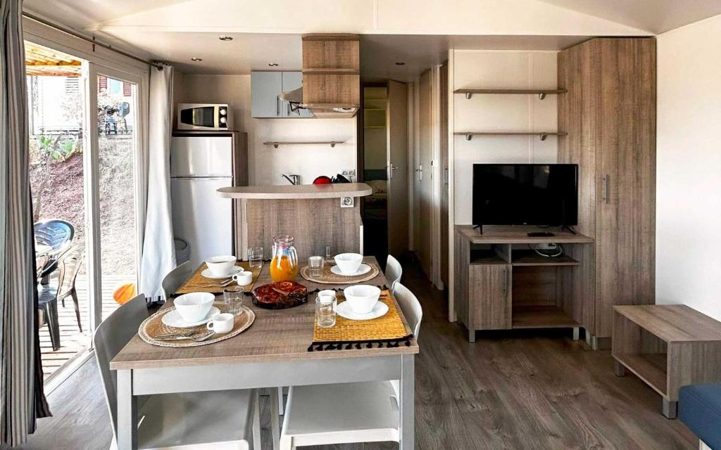 - une cuisine avec une table et une télévision dans la chambre dans l'établissement Camping 5 étoiles - Parc aquatique - eebaff, au Muy