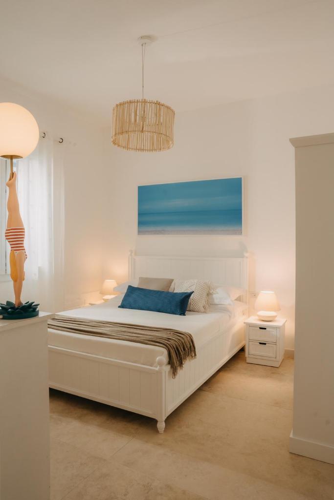 - une chambre avec un grand lit blanc et un lustre dans l'établissement Natoli Beach House & Villas - Villa Giorgia, à Pollina