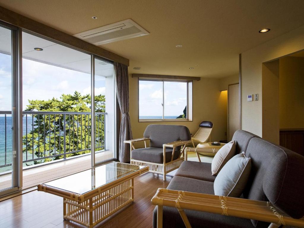 un salon avec un canapé, des chaises et des fenêtres dans l'établissement Yumekaiyu Awajishima, à Sumoto