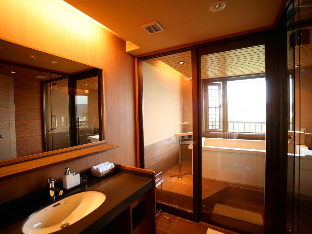 une salle de bain avec un lavabo, un miroir et une douche dans l'établissement Yumekaiyu Awajishima, à Sumoto
