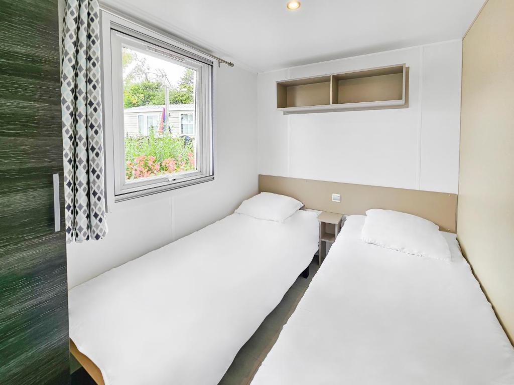 deux lits dans une chambre avec une fenêtre dans l'établissement LOCIMAD, à Litteau
