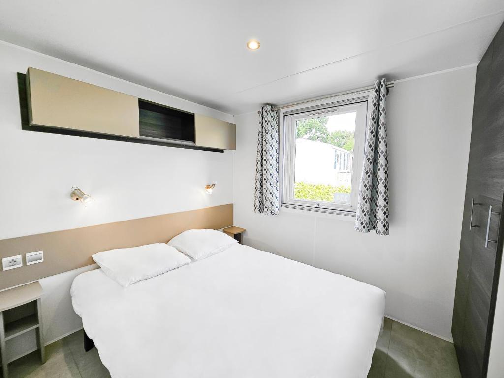 une chambre blanche avec un lit et une fenêtre dans l'établissement LOCIMAD, à Litteau