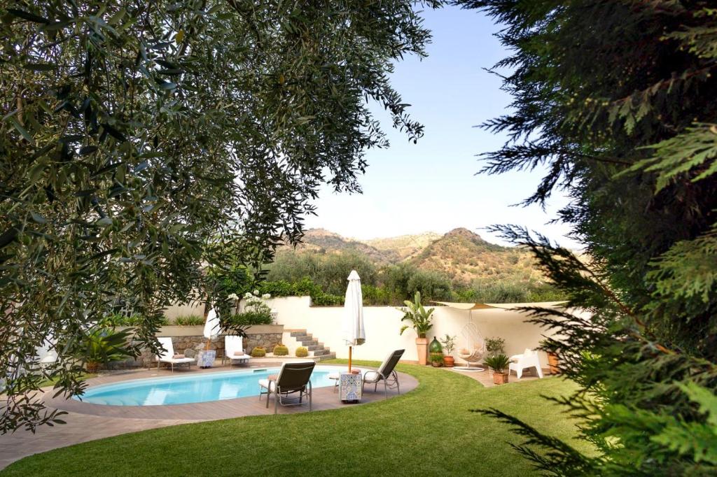 une cour avec une piscine, des chaises et une pelouse dans l'établissement Villa Alcantara di Charme, à Graniti