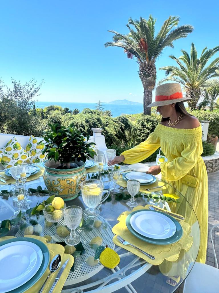 une femme en robe jaune assise à une table dans l'établissement Villa con piscina con 8 camere matrimoniali ad Anacapri, by La Canostra Capri, à Anacapri