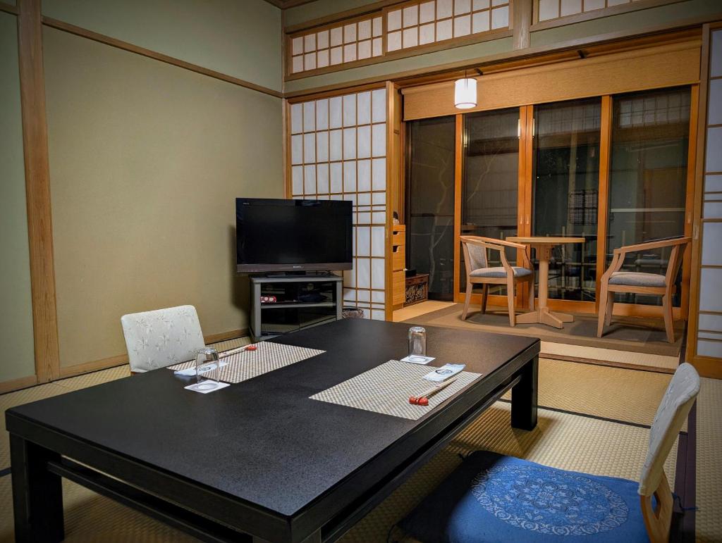 un salon avec une table et une télévision dans l'établissement Ryoso Yufuin Yamadaya, à Yufu