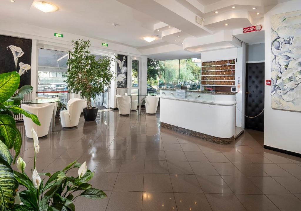 un hall d'un restaurant avec des chaises blanches et des plantes dans l'établissement Hotel Mediterraneo, à Pesaro