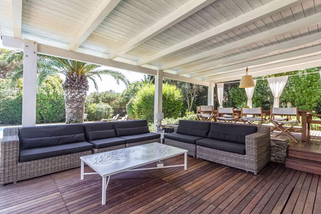 un patio avec des canapés et une table sur une terrasse dans l'établissement CASAVIVA - Villa con piscina privata a Stintino, à Stintino