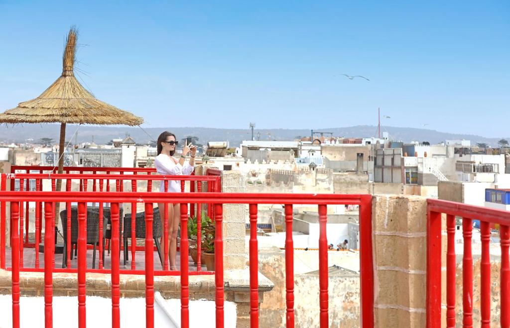 une femme debout sur un balcon avec un parasol dans l'établissement Riad Villa Garance, à Essaouira